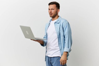 Sıradan tişörtler içinde kafası karışmış, bronzlaşmış yakışıklı bir adam beyaz stüdyo arka planında izole edilmiş bir şekilde duran dizüstü bilgisayarın bozulmasıyla şok olmuş. Uzayın afiş modelini kopyala. Elektronik tamir bilişim konsepti