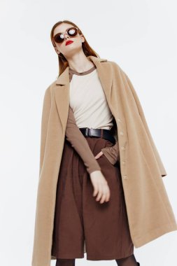 Stüdyoda beyaz bir arka planda gözlüklü, kızıl saçlı, katı bir profesyonel kadın. Katalog fotoğrafçılığı. Yüksek kalite fotoğraf