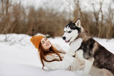 Genç bir kadın kışın bir tarlada temiz hava almış bir köpekle yürüyor. Yüksek kalite fotoğraf