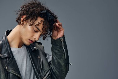 Renkli, bronzlaşmış deri ceketli bir adamın portresi gri arka planda izole edilmiş gözlük takıyor. Güzel moda teklifi. Büyük Mevsimlik Satış Yeni Koleksiyon konsepti. İlan için alanı kopyala