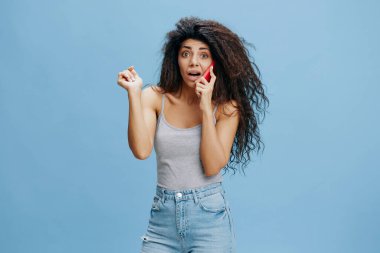 Online, reklam sözleşmesini ara. Şaşırtıcı güzellikteki kıvırcık Latin bayan pembe akıllı telefonu elinde tutuyor, şok edici bilgileri dinliyor, kameraya bak. Güzel teklif. Stüdyo çekimi mavi gökyüzü arka planında. Metin için alanı kopyala