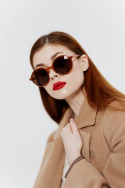 Gözlüklü ve ceketli zarif genç bir kadın beyaz arka planda bir kıyafet kataloğu için poz veriyor. Moda kavramı. Yüksek kalite fotoğraf