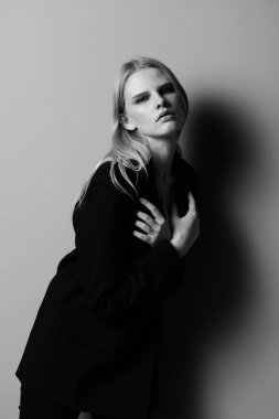 Takım elbiseli sarışın ceketini giyerken kendine sarılıyor. Yüksek kalite fotoğraf