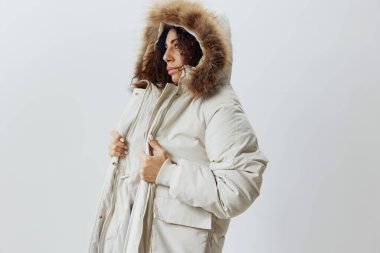 Kıvırcık, kıvırcık, Latin, Kürklü, yumuşak, bej kürklü, kışlık ceket giyen, beyaz stüdyo geçmişine bakan yalnız bir kadın. Moda Satışı Yeni Koleksiyon Dikey Yan Çekim