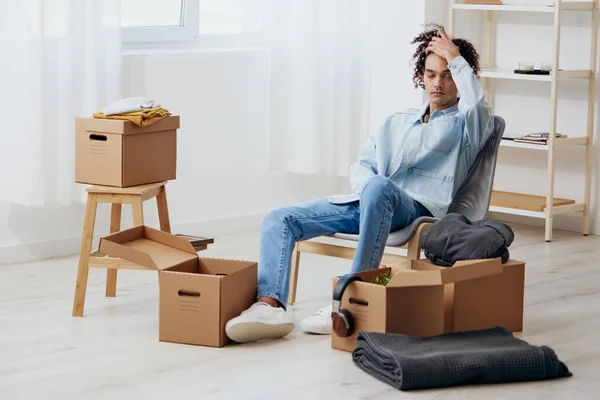 guy with curly hair unpacking things from boxes in the room sorting things out. High quality photo