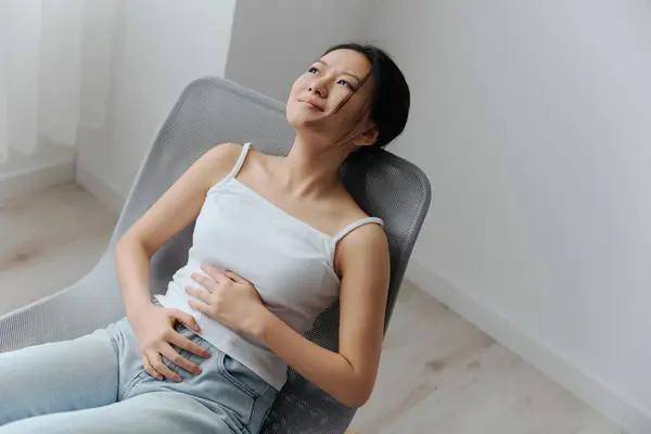 Abortion high Pregnancy lost. Tormented suffering tanned beautiful young Asian woman touch stomach looks up at home interior living room. Injuries Poor health Illness concept. Cool offer Banner