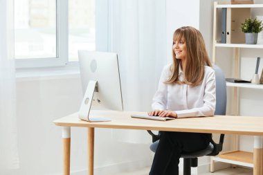 Neşeli, mutlu, tapılası sarışın iş kadını serbest çalışan biri açık modern ofisteki masaüstü bilgisayarında ekran çalışmalarına bakıyor. Happy çalışanı üç aylık rapor yazıyor. Boşluğu kopyala, uzak görev
