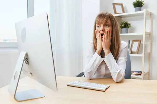 Excited upset adorable blonde businesswoman worker touch chin both hands thinking of problem solution in modern office. Employee work on computer online made a mistake or making decision. Copy space