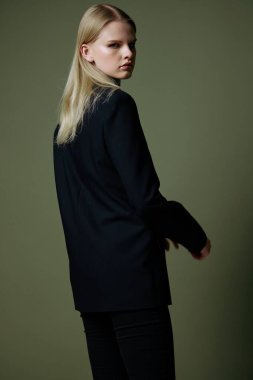 Sarışın, kameraya arkası dönükken poz veriyor. Kıyafet markaları için konsept fotoğraf. Şık takımlar için harika bir teklif. Yüksek kalite fotoğraf