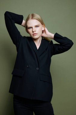 İnanılmaz profesyonel bir model saçını bağlıyor ve kameraya bakıyor. Kıyafet markaları için konsept fotoğraf. Şık takımlar için harika bir teklif. Yüksek kalite fotoğraf