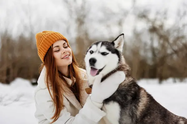 年轻的女人带着狗在户外的田野里散步过冬 高质量的照片 — 图库照片