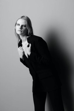 Klasik takım elbiseli güzel bir kız kameraya bakar stüdyoda öne doğru poz verir. Siyah beyaz fotoğraf. Biçim fotoğrafçılığı. Yüksek kalite fotoğraf