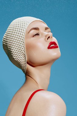 Su parkı için bir teklif. Sevimli bir yüzücü stüdyodaki mavi arka planda gözlerini kapatan yağmur damlalarından hoşlanır. Yakın portre, vesikalık. Yüksek kalite fotoğraf