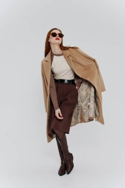 Showroom giyim markasının tasarımı için pankart. Stüdyoda beyaz bir arkaplanda poz veren bej gözlüklü kızıl saçlı şık bir bayan. Yüksek kalite fotoğraf