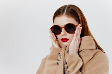 Stüdyoda beyaz bir arka planda gözlüklü genç bir bayanın portresi. Sergi salonu reklamları, tasarımcı kıyafetleri. Yüksek kalite fotoğraf