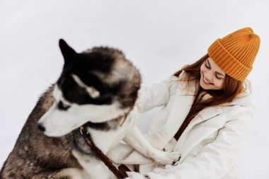 Kışın bir tarlada bir köpekle yürüyüş yapan neşeli bir kadın. Yüksek kalite fotoğraf