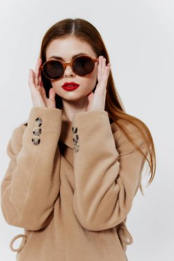 Kızıl saçlı profesyonel bir model, bir giyim markası dergisi için ceket ve gözlüklü poz veriyor. Yüksek kalite fotoğraf