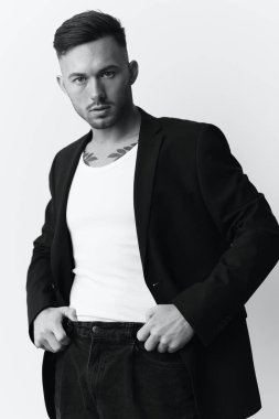Fotoğrafları modelliyorum. Kendine güvenen narsist, çekici, klasik takım elbiseli yakışıklı adam beyaz stüdyo arka planında yalnız poz veren kemerin üzerinde el ele tutuşuyor. Siyah beyaz kavramı. Moda teklifi. Boşluğu kopyala