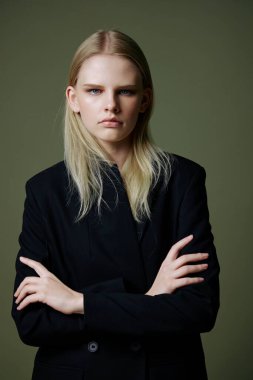 Kadın hareketi konsepti. Kendine güveni tam başarılı bir kız kollarını göğsünde kavuşturur ve yeşil arka planda poz veren kameraya bakar. Yüksek kalite fotoğraf