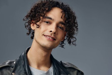 Gri stüdyo arka planında izole edilmiş, bronzlaşmış kıvırcık deri ceketin portresi. Güzel moda teklifi. Büyük Mevsimlik Satış Yeni Koleksiyon konsepti. İlan için alanı kopyala