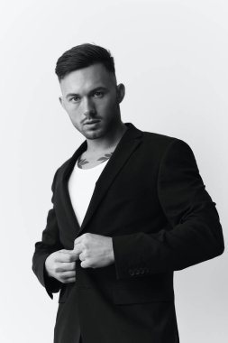 Fotoğrafları modelliyorum. Kendine güvenen, kendine güvenen, klasik takım elbiseli yakışıklı bir adam beyaz stüdyo arka planında yalnız poz veriyor. Siyah ve Beyaz konsepti. Moda teklifi. Boşluğu kopyala