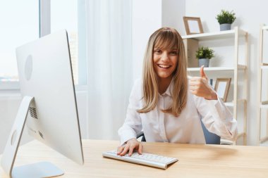 Happy, sarışın, tapılası, serbest çalışan bir iş kadınından hoşlanıyordu. Kameraya bak. Modern ofiste başparmak hareketi yap. İnternette çalışan çalışanlar başarılı bir kariyerin tadını çıkarıyorlar. Boşluğu kopyala