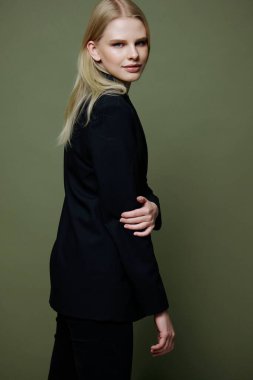 Çekici bir kız omzunun arkasından kameraya döner. Stüdyoda yeşil arka planda poz veren güzel bir model. Yüksek kalite fotoğraf