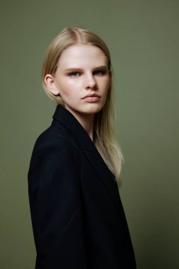 Markalar için güzel pankart. Çekici, havalı profesyonel bir model yarım dönüşle poz veriyor ve stüdyoda yeşil zeytinli arka plandaki kameraya bakıyor. Yüksek kalite fotoğraf