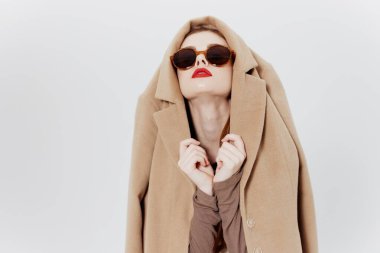 Kavramsal katalog fotoğrafı. Gözlüklü ve kafasında ceket olan bir kız beyaz arka planda poz veriyor. Yüksek kalite fotoğraf