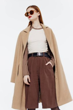 Stüdyoda beyaz bir arka planda gözlüklü, kızıl saçlı, katı bir profesyonel kadın. Katalog fotoğrafçılığı. Yüksek kalite fotoğraf