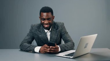 Erkek iş adamı Afro-Amerikan iş yerinde telefonda bir mesaj yazıyor ve gülümsüyor. Yüksek kalite 4k görüntü