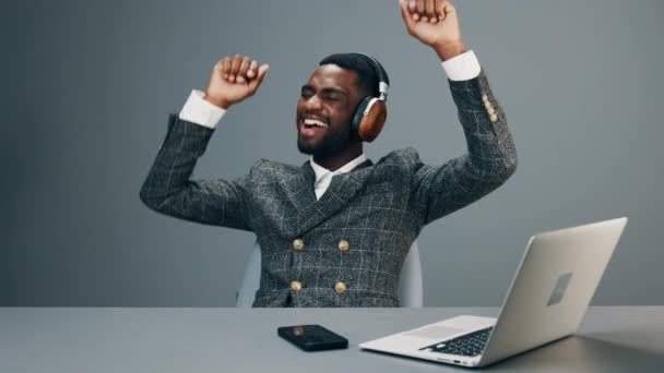 Afroamerikansk Affärsman Sitter Vid Sitt Skrivbord Kontoret Hörlurar Och Lyssnar — Stockvideo