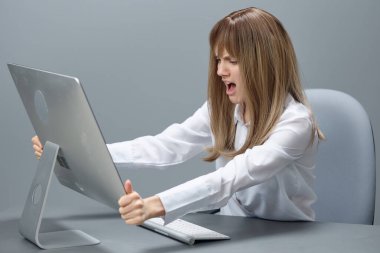 Gri modern ofisteki işyerinde bilgisayar hatası yüzünden öfkeli sarışın iş kadını öfkeyle masaüstüne bağırıyor. Teknoloji ve Operasyon Problem Kavramı. Boşluğu kopyala
