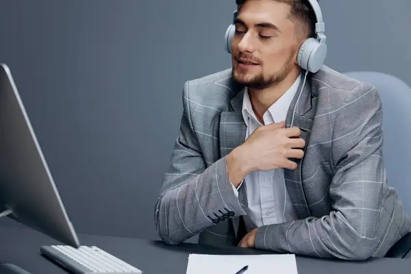 handsome man working at the computer in headphones in the office Gray background. High quality photo