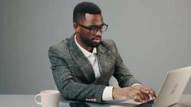 Bilgisayarlı gözlüklü Afrikalı Amerikalı işadamı, ofisinde, masasında bir kupa kahveyle çalışıyor ve yorgun. Yüksek kalite 4k görüntü