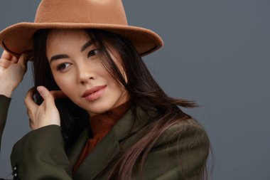 Güzel bir kadın şık bir takım elbise içinde bej şapkalı stüdyo modeli poz veriyor. Yüksek kalite fotoğraf