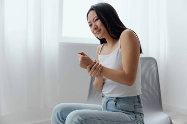 Bronzlaşmış, bronzlaşmış, genç bir Asyalı kadının acı dolu bileğini oturma odasında tutarak acı çekmesinden muzdarip. Yaralar Kötü Sağlık Hastalığı konsepti. Güzel teklif Banner.