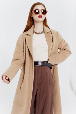 Stüdyoda beyaz bir arka planda gözlüklü, kızıl saçlı, katı bir profesyonel kadın. Katalog fotoğrafçılığı. Yüksek kalite fotoğraf