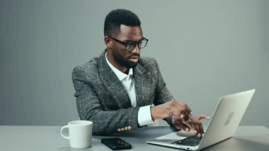 Bilgisayarlı gözlüklü Afrikalı Amerikalı işadamı, ofisinde, masasında bir kupa kahveyle çalışıyor ve yorgun. Yüksek kalite 4k görüntü
