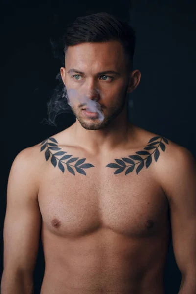 Modelling snapshots. Pensive serious tanned attractive handsome naked man thinking looks aside smoking posing isolated in black studio background. Fashion offer. Copy space for ad. Closeup