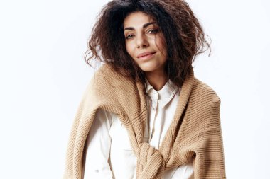 Beyaz Stüdyo Duvarı 'nın arka planındaki kameraya bakan, bej renkli, kalın kazaklı beyaz tişörtlü, kıvırcık Latin bir kadının portresi. Moda Mevsimsel Satış Yeni Koleksiyon Konsepti. Boşluğu kopyala