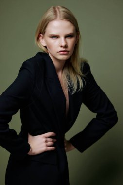 Şık, kendine güvenen genç bir kız yeşil arka planda poz veren kameraya bakarken ellerini belinde tutuyor. Yüksek kalite fotoğraf