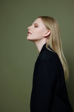 Stüdyonun yeşil zeytin arka planında profilde poz veren şık, çekici bir kız. Markalar için güzel pankart. Yüksek kalite fotoğraf