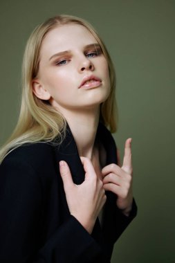 Kollarını göğsünde bağlayan bir sarışının tasmasından ceketini tutan yakın bir portresi. Yüksek kalite fotoğraf