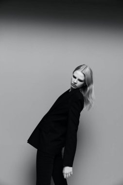 Güzellik geriye doğru eğiliyor, ellerini indiriyor. Takım elbiseli şık bir bayan stüdyoda uçan saçlarla poz veriyor. Markalar için tarz kavramı. Yüksek kalite fotoğraf