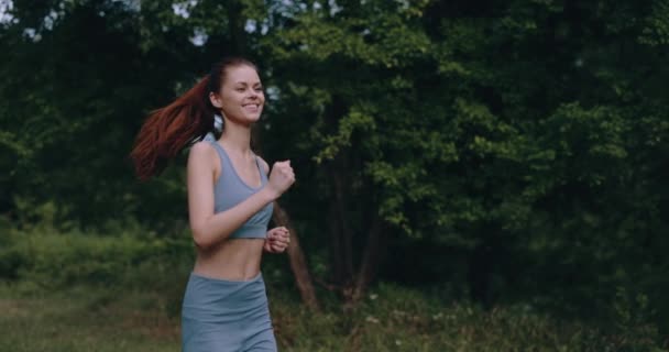 公園で朝のジョギングをしている女性は 木の背景を追跡しています 高品質の4K映像 — ストック動画