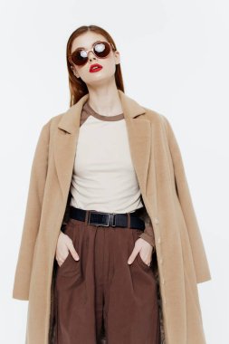 Beyaz arka planda gözlüklü ve ceketli şık kızıl saçlı bir bayan. Yüksek kalite fotoğraf