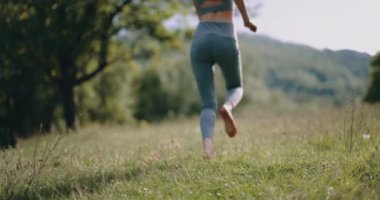 Açık hava parkında yeşil çimlerin üzerinde çıplak ayakla koşan bir kadın. Doğayla uyum kavramı. Yüksek kalite 4k görüntü