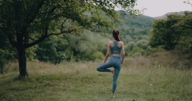 Parkta eşofmanla yoga yapan sporcu bir kadın. Meditasyon bir yaşam tarzı. Yüksek kalite 4k görüntü