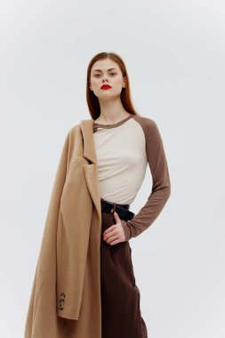 Stüdyonun beyaz arka planındaki kahverengi tondaki güzellik, şık kıyafetlerin sergi salonunun reklamını yapıyor. Katalog fotoğrafçılığı. Yüksek kalite fotoğraf